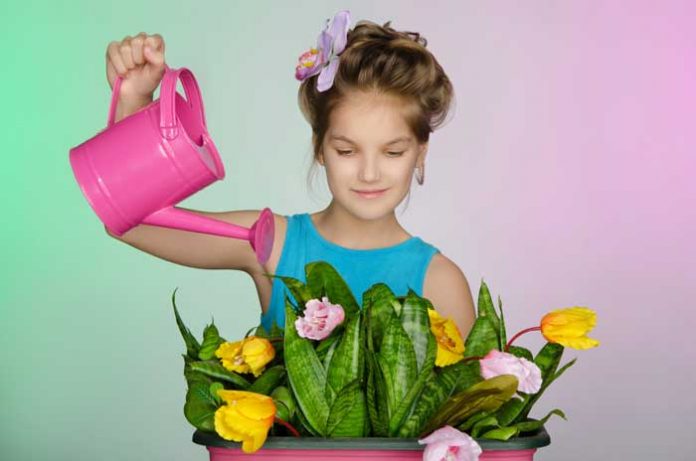 девочка поливает комнатные растения в детской